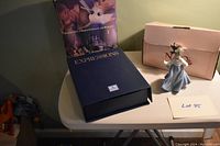 Overview of Lladro figurine with dove, Lladro Society welcome kit binder, and original box on a table.