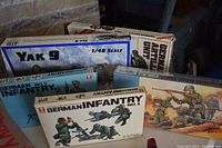 Image showing five military model kits including 1/48 scale Yak 9 aircraft and various German infantry soldier kits, all sealed in boxes, displayed closely together.