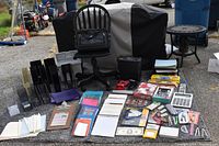 Photo showing entire lot including briefcase, shredder, chair, rug, calculators, and assorted office supplies spread over rug on pavement.
