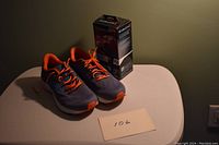 Pair of Ravenna running shoes with Remington electric shaver box on a white surface against a green wall.