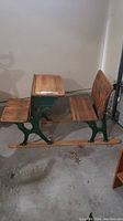 Side view of the antique children's school desk showing hardwood seat, desktop and green iron sled base.