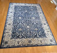 Top-down photo showing the entire decorative navy and cream area rug laid flat on hardwood floor.