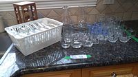 Overview of glass spice jars, drinking glasses, and carafes arranged on countertop with wooden spice rack visible