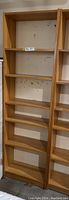 Tall pine bookshelf with six shelves, showing natural wood grain and open shelving format. Visible marks on back panel.