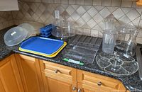 Photo of countertop showing microwave food covers, ice cube trays, cake stand with lid, serving trays, and more kitchenware items as detailed.