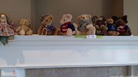 Wide shot of seven small stuffed animals arranged on a ledge including bears and a deer, showing overall lot contents.