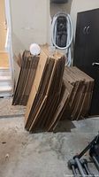 Image showing stacks of flattened cardboard boxes in various sizes leaning against a wall and wardrobe box with an attached hanging bar visible.