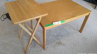 Two wooden tables side by side, foldable TV tray table on left and small all-purpose table on right.