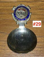 Full view of the tea caddy spoon showing the circular enameled medallion with King George VI and Queen Elizabeth profile busts under crowns and commemorative text around the rim.