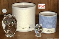 Two crystal owl figurines displayed in front of original boxes with product codes and labels