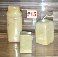 Three carved stone Chinese chop seals displayed on a wooden surface beneath glass, varying in height from 1.5 inches to 0.75 inches.