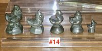 Five antique Asian figural bronze scale weights displayed in a row, showing varying sizes and bird designs