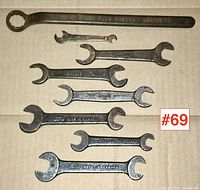 Lot of eight vintage Ford wrenches, various sizes, arranged flat on cardboard with clear markings visible, 'model T-1917' and 'Made in Canada' noted.