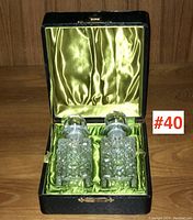 Pair of Edwardian cut glass scent bottles with round glass stoppers displayed in original black fitted box with green satin lining.