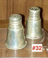 Front standing view of the pair of tarnished sterling silver salt and pepper shakers with #32 label.
