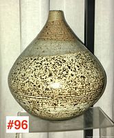 Front view of a studio pottery vase showing its rounded body and narrow neck with speckled glaze pattern.