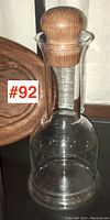 Front view of the clear glass carafe with the wooden stopper in place, showing the smooth contours and round stopper.