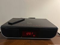 Front view of Roth Alfie DVD player powered on showing red LED clock display and remote on top.