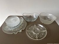 Photo showing two glass bowls, divided serving plate, large platters, and stack of small plates.