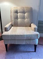 Front view of the cream colored floral pattern lounge chair with tufted cushions and wooden legs.