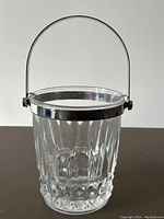 Mini crystal ice bucket showing faceted crystal texture, metal rim, and wire handle from front view.
