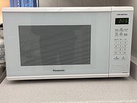 Front view of white Panasonic microwave oven with door closed and control panel visible showing digital time 2:26.