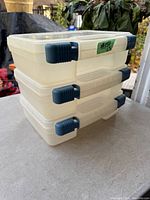 Stack of three plastic storage cases showing closed view with blue latch handles and carrying handles on top.