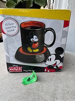 Front of box showing Mickey Mouse mug on the warmer and overall packaging
