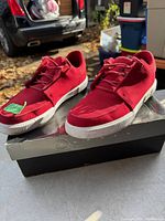 Red Jordan Air shoes placed on their black shoebox, outdoor lighting shows the bright red upper and white sole.