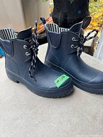Side view of black ladies rubber boots showing lace-up front, pull tab, and striped inner lining.