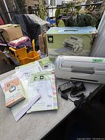 Full view of the Cricut Personal Electronic Cutter with original box, instruction manuals, power adapter, and a booklet.