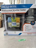 Front of box showing the Acurite Professional Weather Center, digital display with various weather metrics including wind speed, temperature, humidity, and barometric pressure.