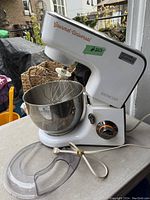 White Sencor Gourmet Universal stand mixer with stainless steel bowl on table, with clear splash guard and cord.