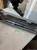 Torque wrench inside molded plastic case on a table, showing full wrench and handle details.