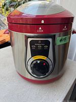 Front view of the red and stainless steel Wolfgang Puck pressure cooker showing the control knob and indicator lights.