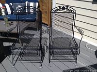 Two black metal mesh rocking chairs side by side, showing decorative back and rocking base