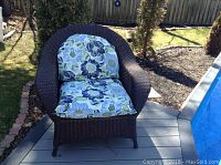 Front view of resin wicker chair with floral cushion on deck