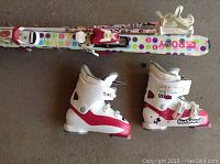 White/pink Roxy skis with multicolor polka dots, adjustable bindings, two Rossignol boots