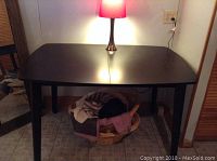 Front view of dark wood extension dining table with lamp on top, showing center extension seam and some surface scratches.