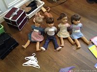 Four American Girl 18-inch dolls seated on floor