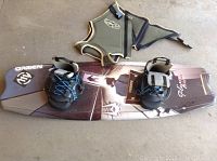 OBrien wakeboard with boots attached and olive green life vest laid out on ground
