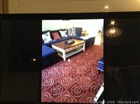 View of the carpet in a living room setting under coffee table and seating furniture, showcasing its color and swirl design.