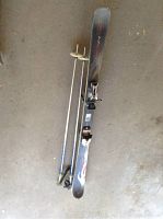 Top view of one Dynastar freestyle ski with bindings and two ski poles on a concrete floor.