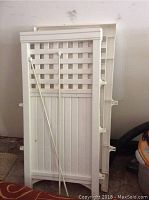 Two white plastic privacy fence panels, stacked, showing lattice top and solid bottom sections.