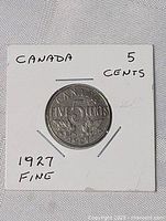 Photo of the 1927 Canadian five cents nickel coin in circulated condition displayed in a white card holder with markings: 'CANADA 5 CENTS 1927 FINE'.