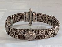 Front view of the antique sterling silver woven chain bracelet showing the central medallion with a raised figural design and the clasp.