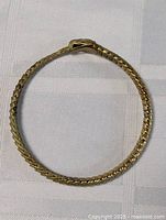 Top view of the round gold plated snake themed bracelet showing the scale texture and clasp resembling a snake head.