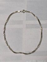 Full view of sterling silver anklet bracelet laid on fabric showing entire chain and clasp.