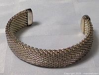 Front angle view of the thick thatched sterling silver bracelet on a white textured surface showing the bracelet's chain pattern and shape.