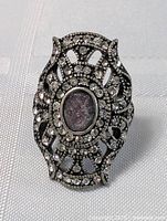 Front view of vintage gothic encrusted ring with central oval stone and filigree rhinestone pattern.